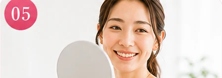 手鏡を見て笑顔になる女性
